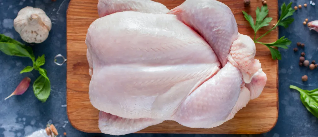 Overhead view of a raw turkey on a food preparation board surround by herbs and spices