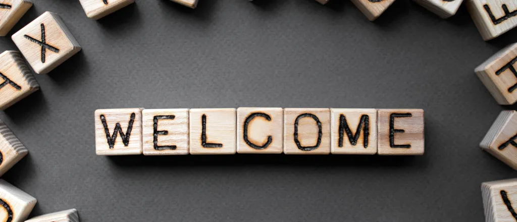 Assorted wooden blocks with letters on the side, surrounding wooden blocks spelling the word "welcome"