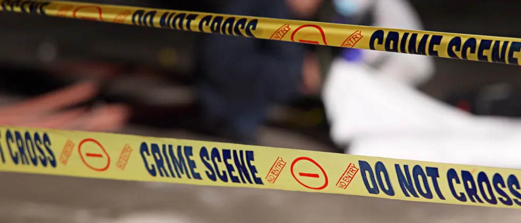 Close up of crime scene tape, which has the words "Do not cross," "No entry," and "Crime scene" printed in a repeating pattern.