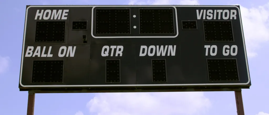 Football scoreboard in the foreground against a partly cloudy sky.