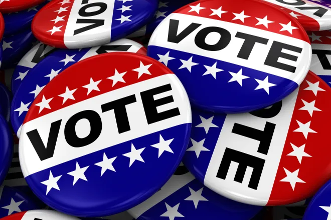 Pile of red, white, and blue lapel pins with the word "Vote"