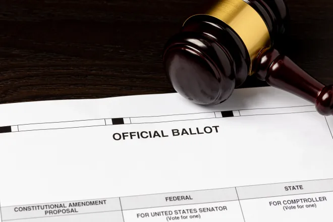 Court judge's gavel resting on an election ballot.