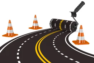 Concept image of a paint roller creating a four-lane road. Construction cones are at the sides.