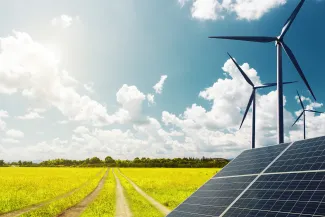 Solar panels and wind turbines near a vehicle path crossing a field