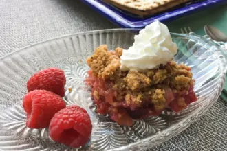 Glass serving dish of Passover rhubarb cobbler with three fresh raspberries.