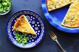 Pie pan with a Magic Crust Quiche. A slice has been removed and set on a nearby serving plate with a small amount of broccoli.